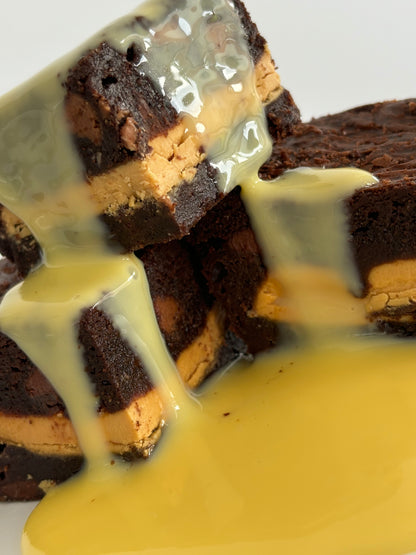 Gooey chocolate brownies stuffed with Caramilk chocolate with a custard drizzle pouring down