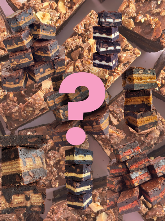 Stacks of fudgy, gooey chocolate brownie stuffed with different biscuits and chocolate bars on a background of chocolate brownies with crushed up Ferrero Rochers on top